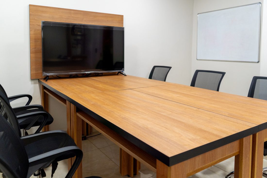 Sala de reunião com mesa grande e televisão
